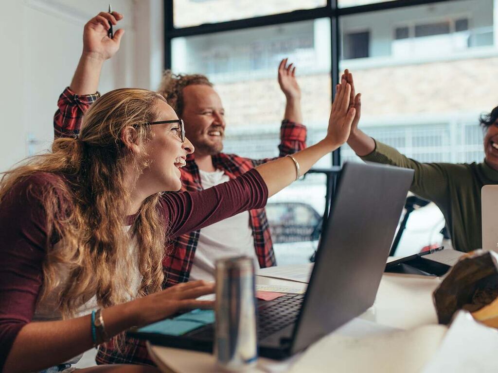 equipe comemorando em escritório, representando a boa comunicação com o cliente